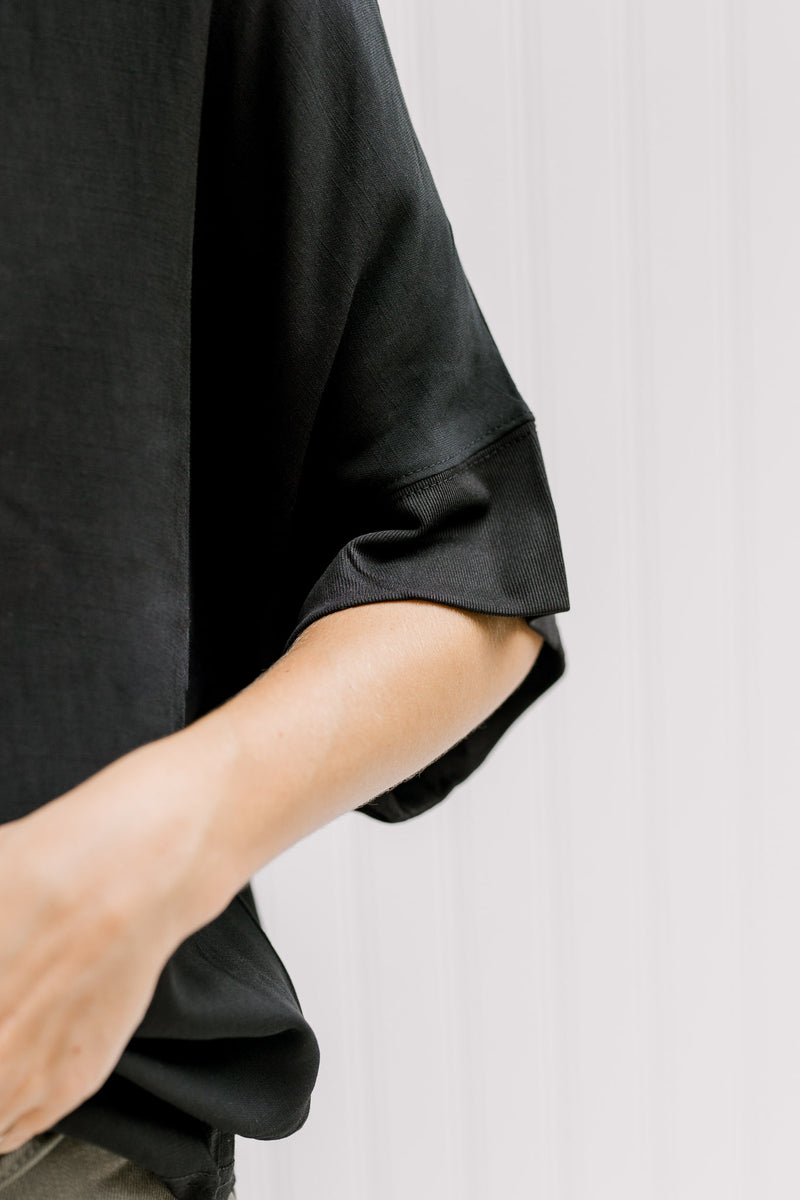 Close up of short sleeve with ruffle detail on a solid  black top