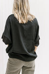 Back view of Model wearing a black top with a round neck and short sleeves with a ruffle detail.