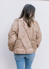 Back view of Model wearing a taupe puffer jacket with flower detail and long sleeves.