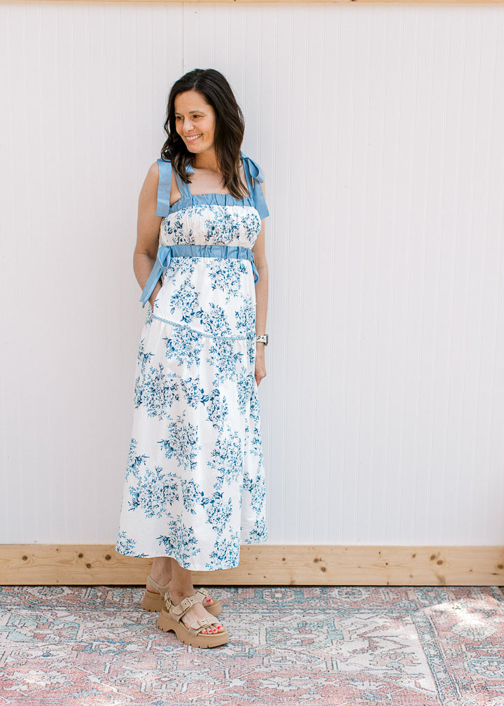 Model wearing a white midi with blue floral, elastic bands at bust and tie sides and straps.
