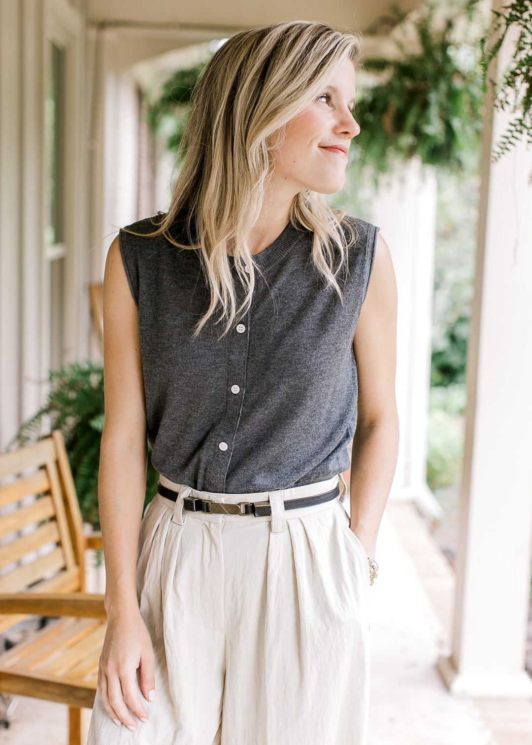 Model wearing a charcoal sleeveless knit with rolled armholes button front and round neck. 
