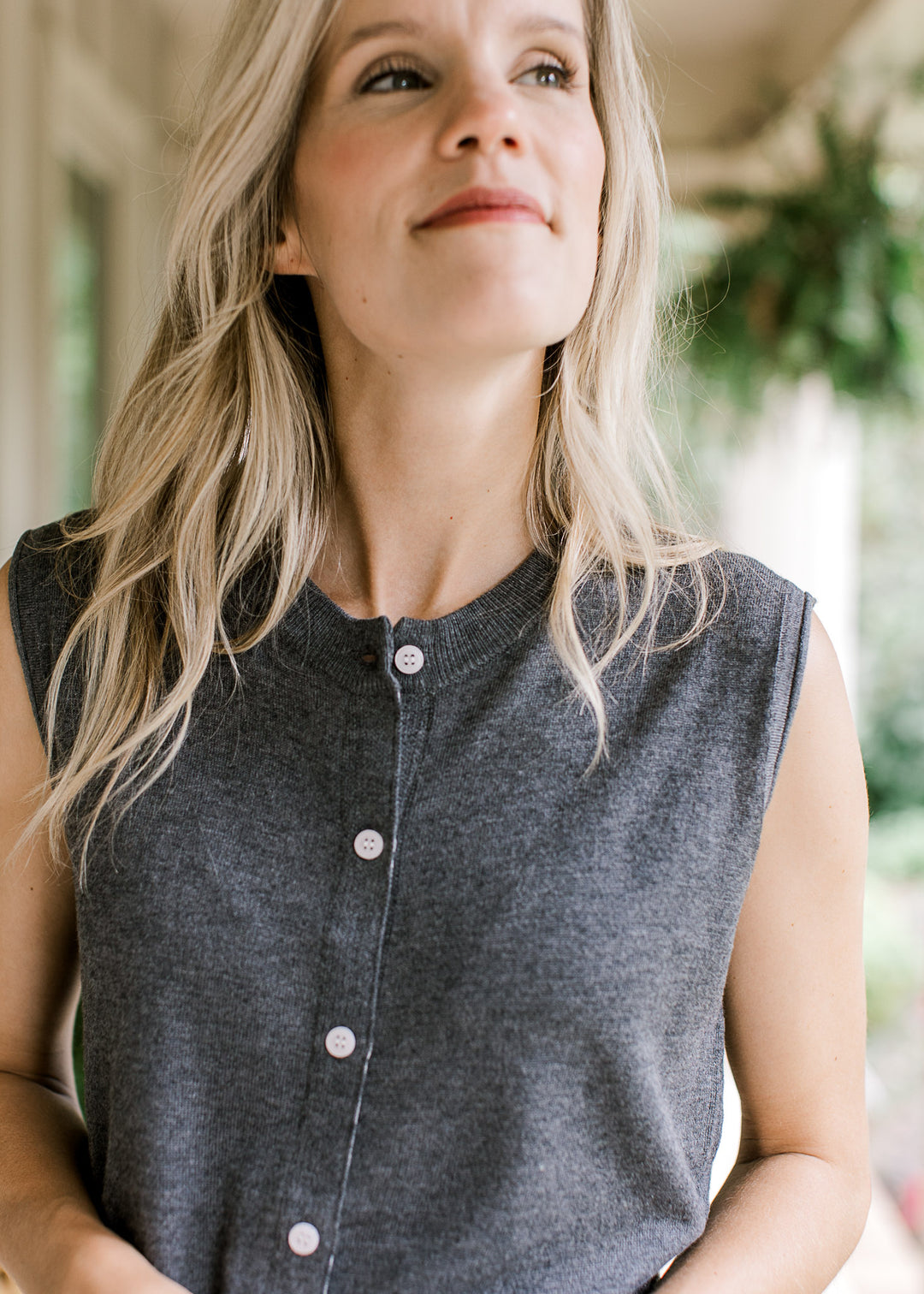 Close up of round neck and button front on a charcoal knit sleeveless blouse. 