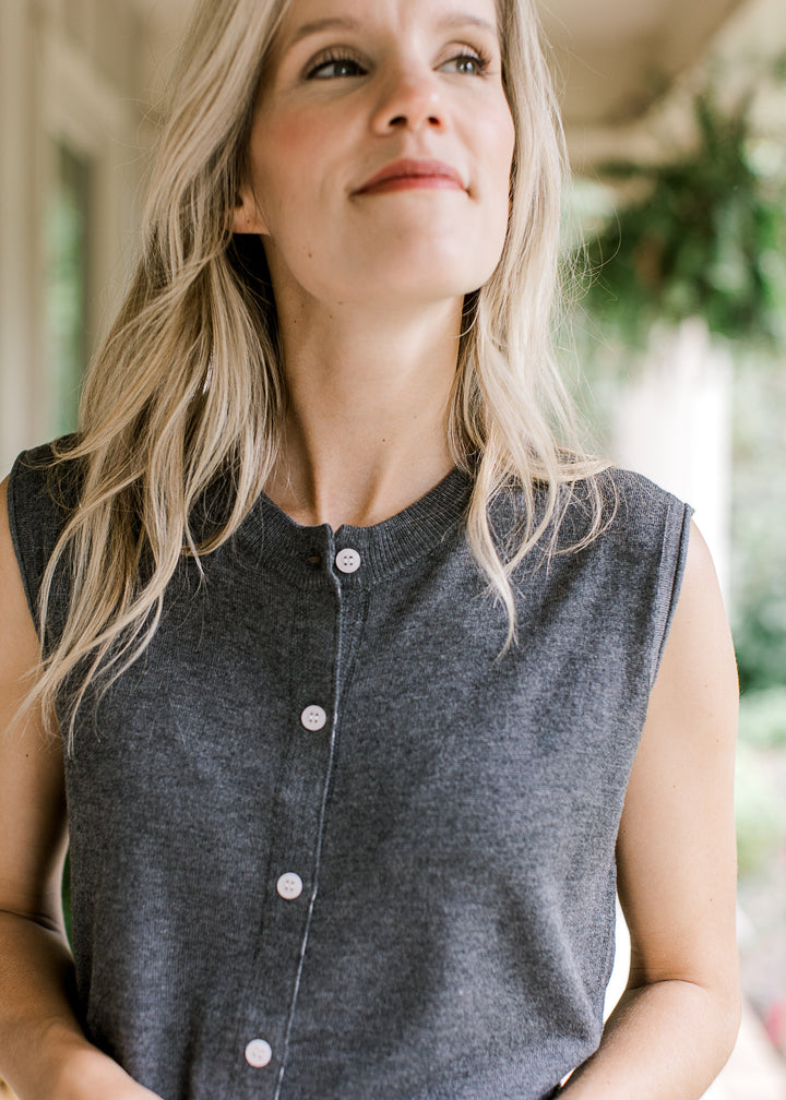 Close up of round neck and button front on a charcoal knit sleeveless blouse. 