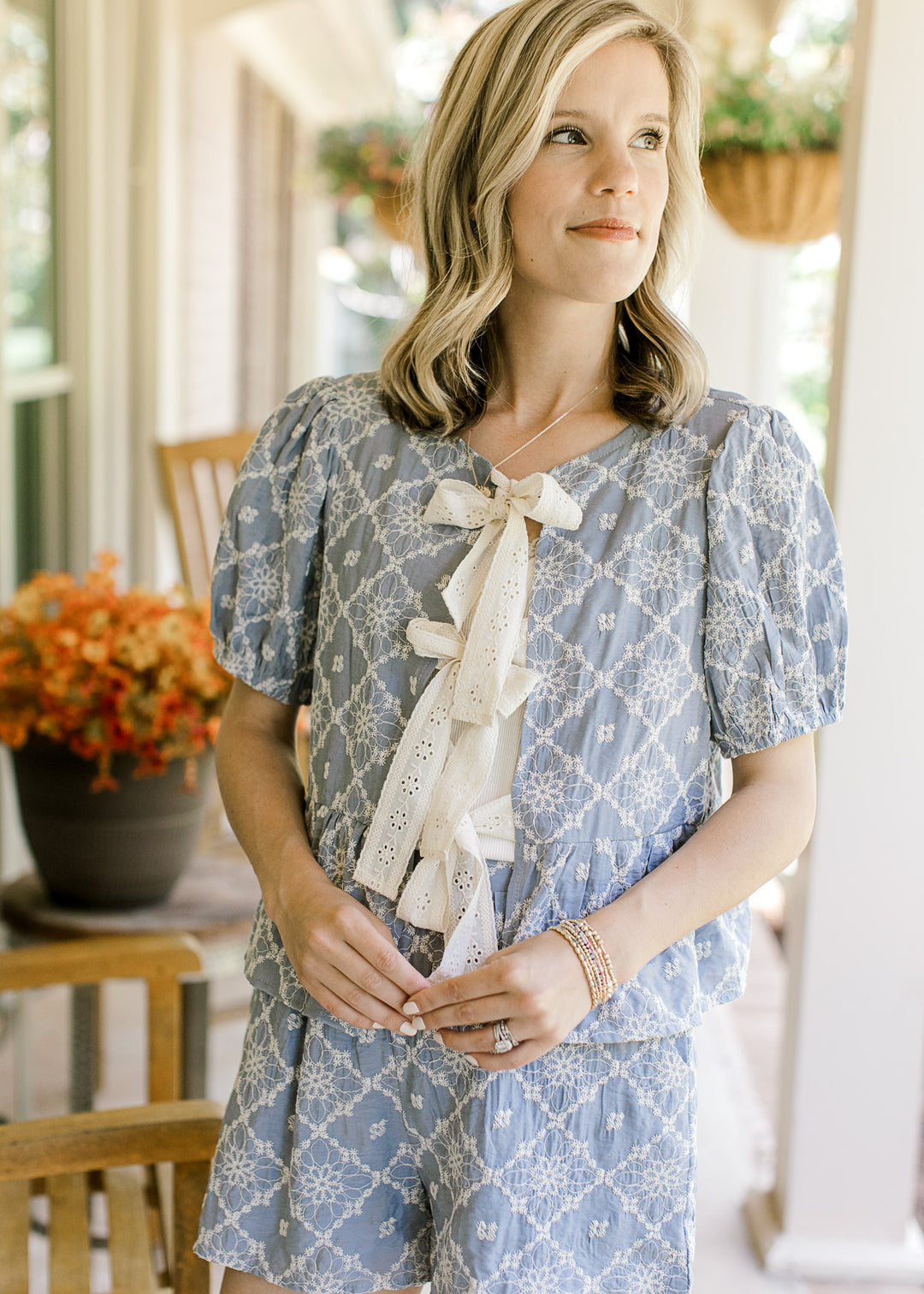 Model wearing a pale blue short sleeve with cream floral, peplum fit and short sleeves. 