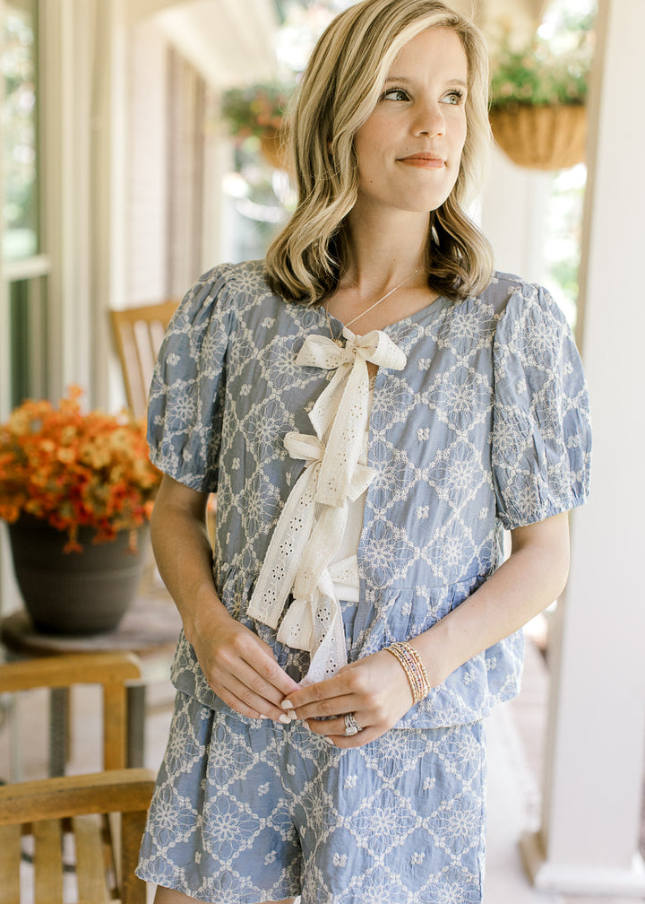 Model wearing a pale blue short sleeve with cream floral, peplum fit and short sleeves. 