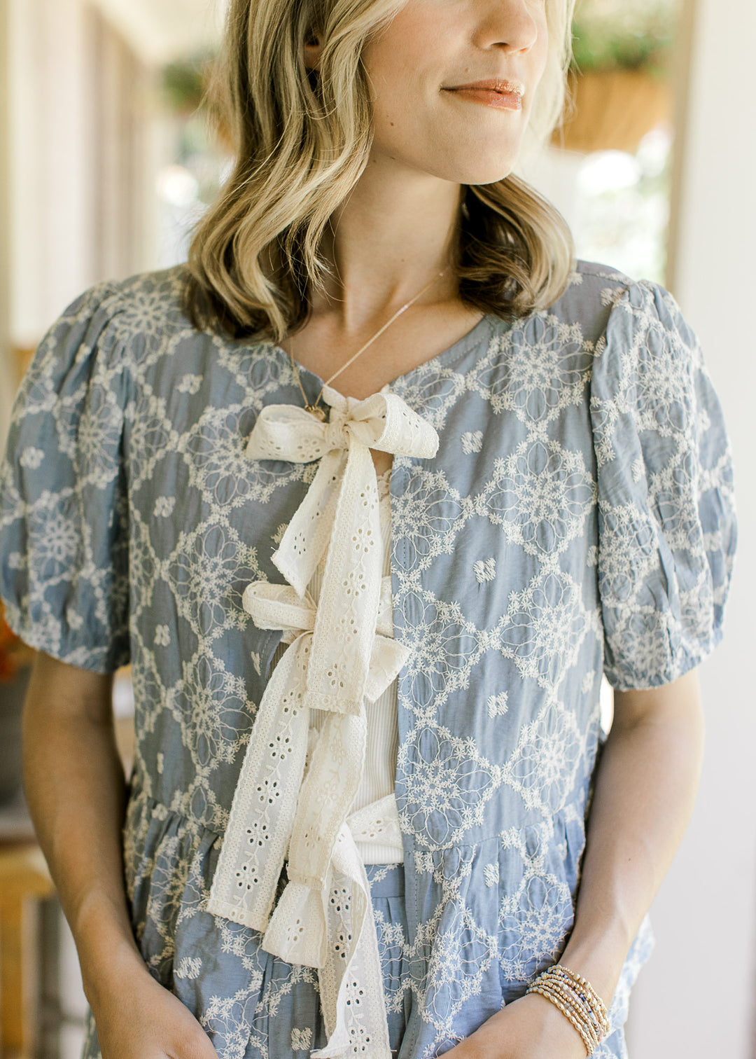 Close up of cream three tie closure and short sleeves on the top of a blue set with cream floral.