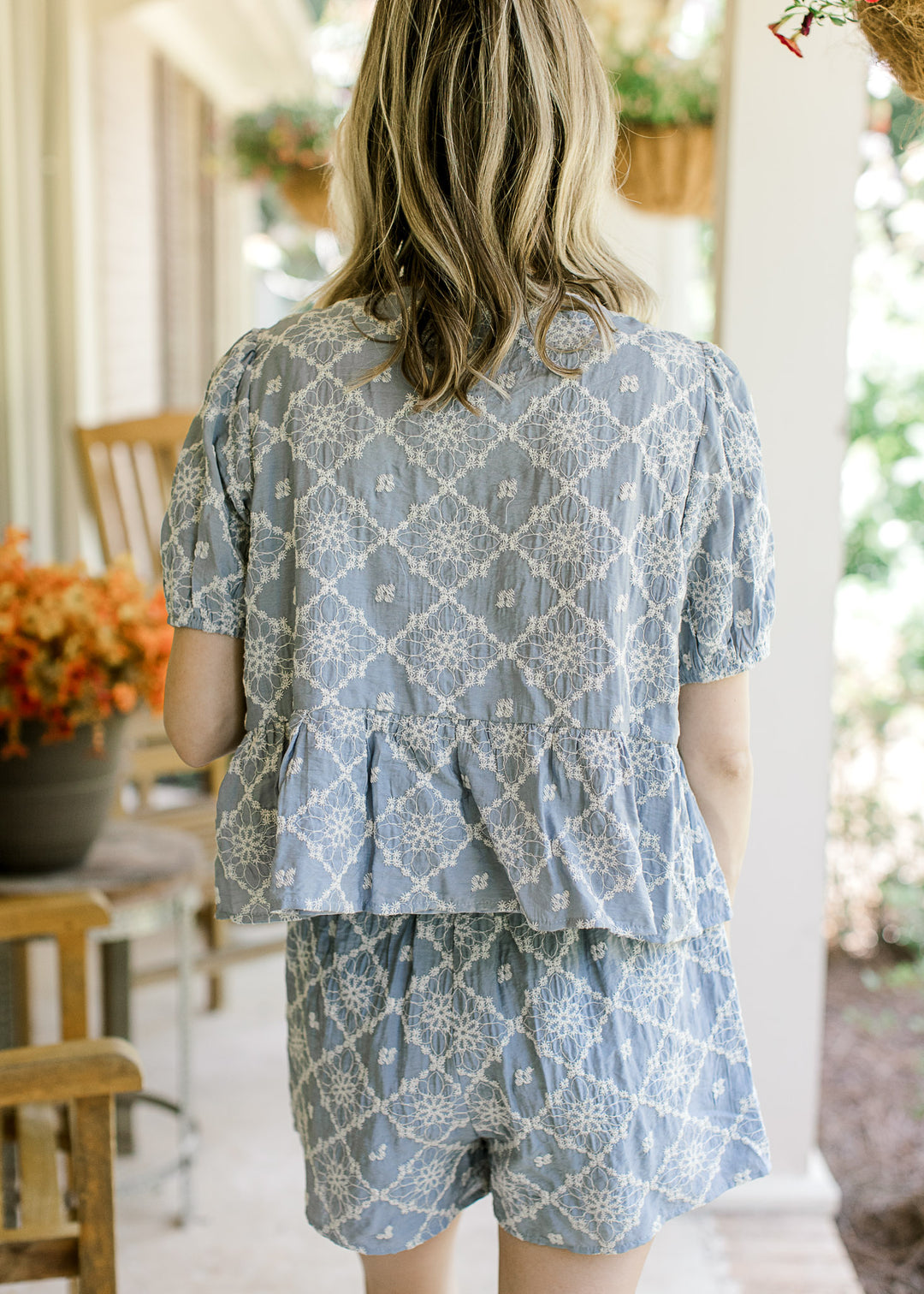 Back view of Model wearing a light blue set with cream embroidered floral shorts and short sleeves.