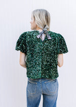 Back view of shimmer tie closure on an emerald green sequin top with short puff sleeves.