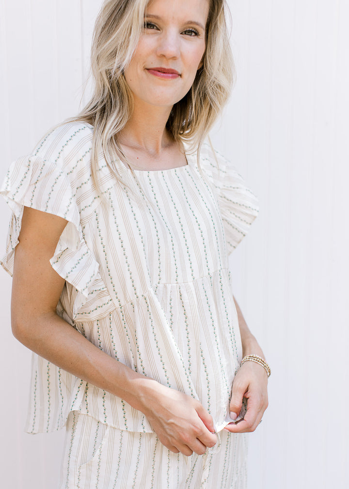 Model wearing a cream set, the top has a square neck and ruffle cap sleeves with wide leg bottoms.