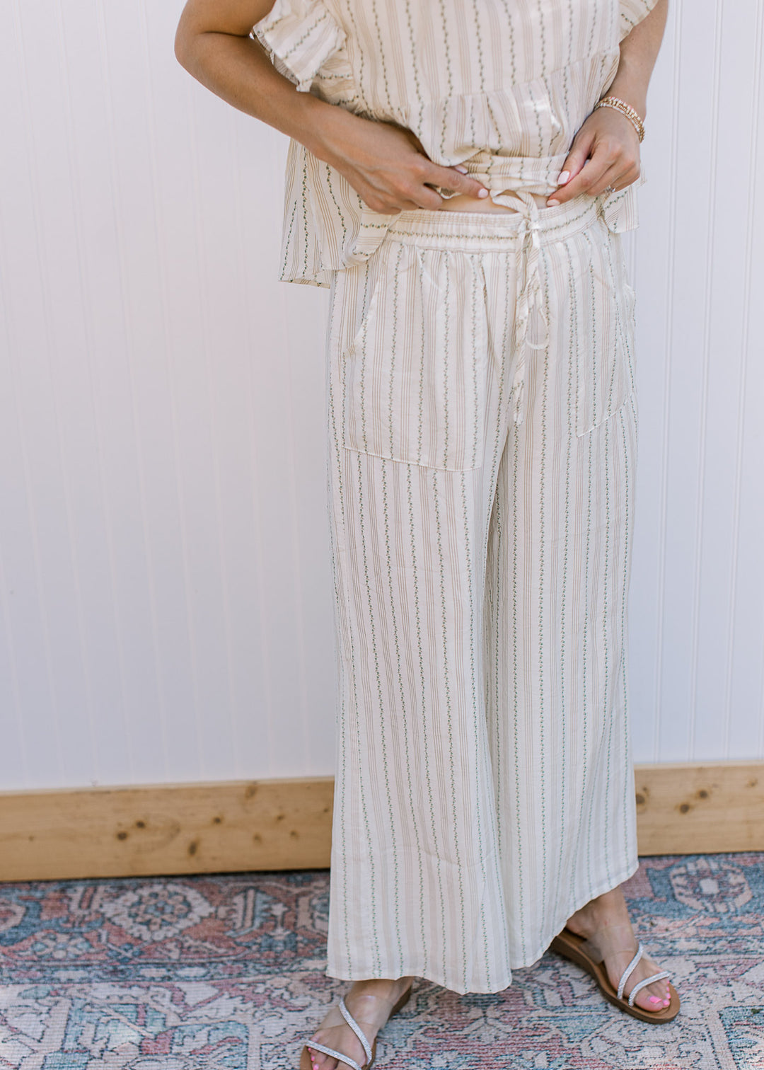 Close up of elastic band with tie and pockets on a matching cream set with green and tan stripes.