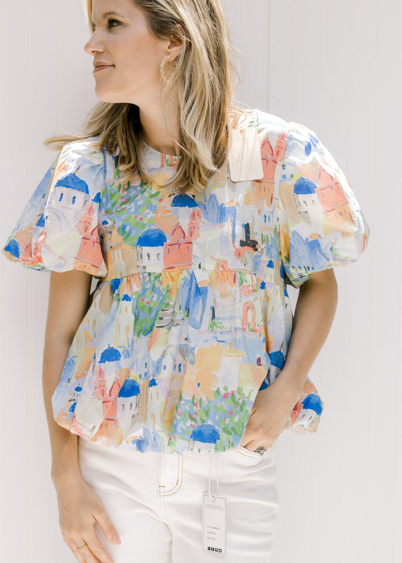 Model wearing a cotton v-neck top with an abstract watercolor building design and puff short sleeves