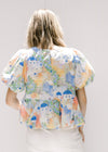 Back view of model waring a v-neck top with an abstract watercolor building design and short sleeves