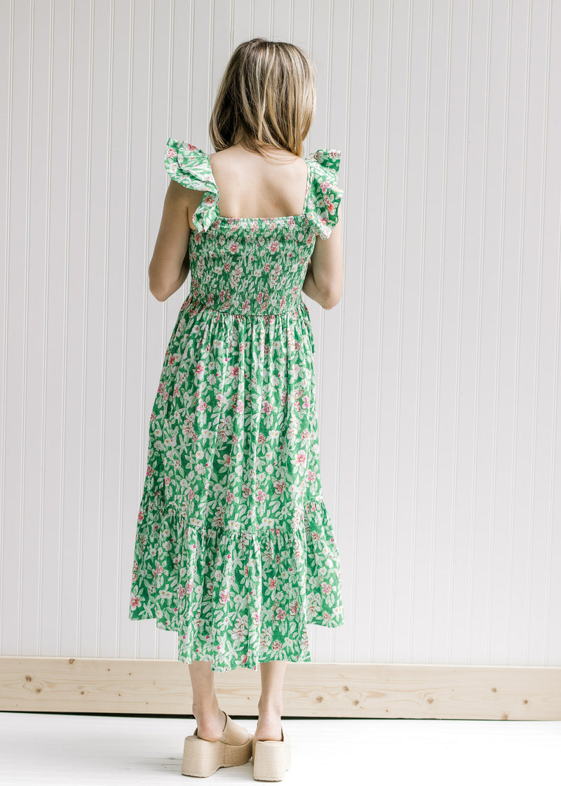 Back view of Model wearing a green midi dress with pink floral, a smocked bodice and a square neck.