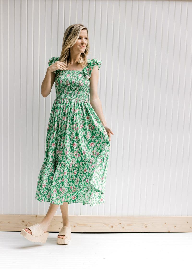 Model wearing wedges with a green midi dress with pink floral, a smocked bodice and a square neck.