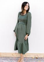 Model wearing an evergreen dress with bubble long sleeves, square neck and flowy skirt.