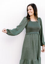 Model wearing an evergreen dress with a Fitted top, flowy bottom and bubble long sleeves. 