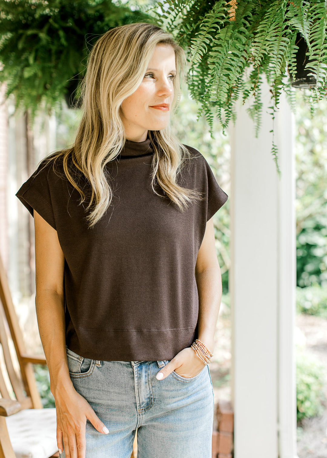 Model wearing a mocha lightweight sweater with extended sleeves and a mock neck.  