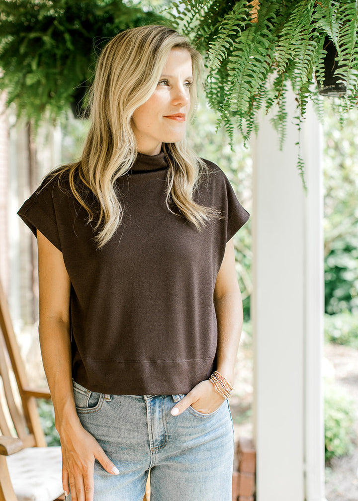 Model wearing a mocha lightweight sweater with extended sleeves and a mock neck.  