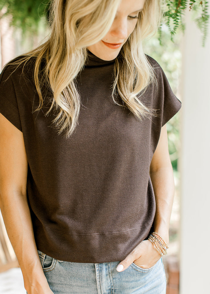 Model wearing a mocha sweater with extended sleeves and a mock neck.  