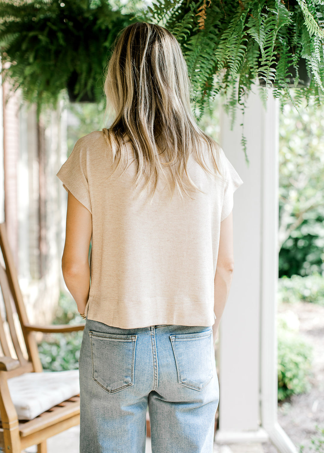 Back view of Model wearing a slightly cropped oatmeal sweater with extended sleeves. 