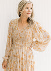 Close up of taupe maxi with sheer long sleeves and yellow and light brown floral pattern. 