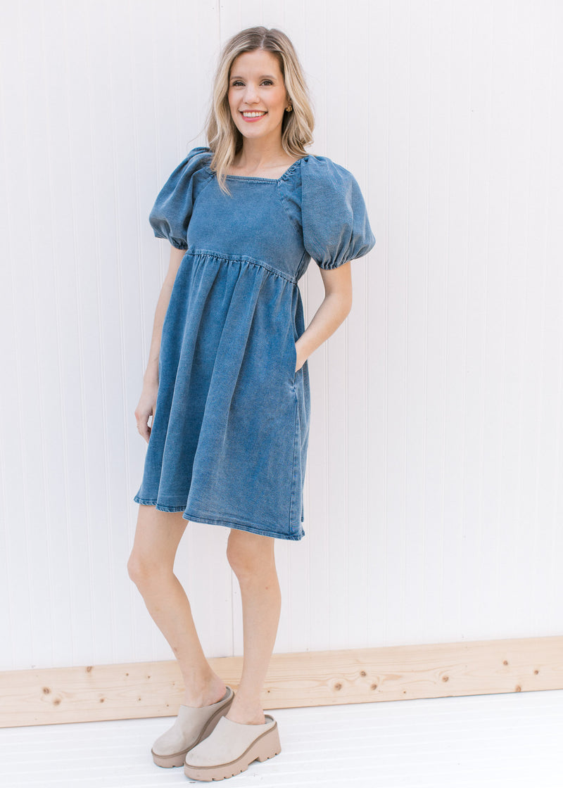Model wearing mules with a medium washed denim dress with bubble short sleeves and a square neck.