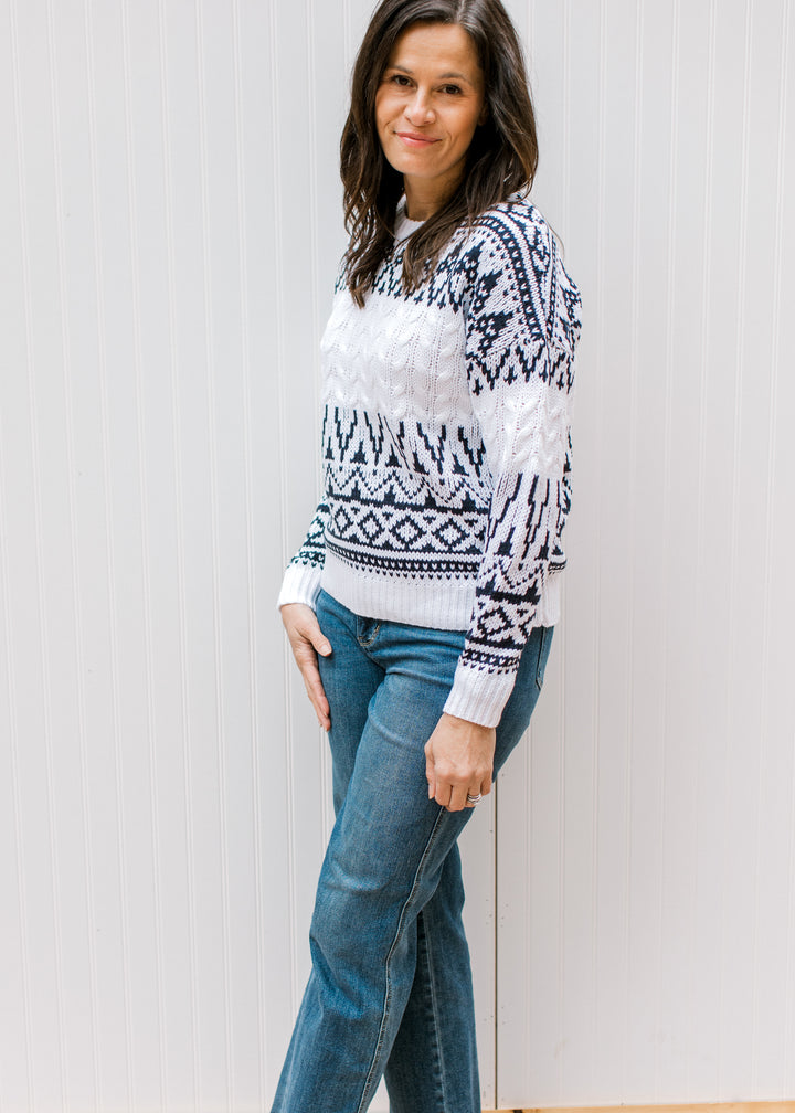 Model wearing jeans and a cream sweater with a navy Fair Isle design, round neck and long sleeves. 