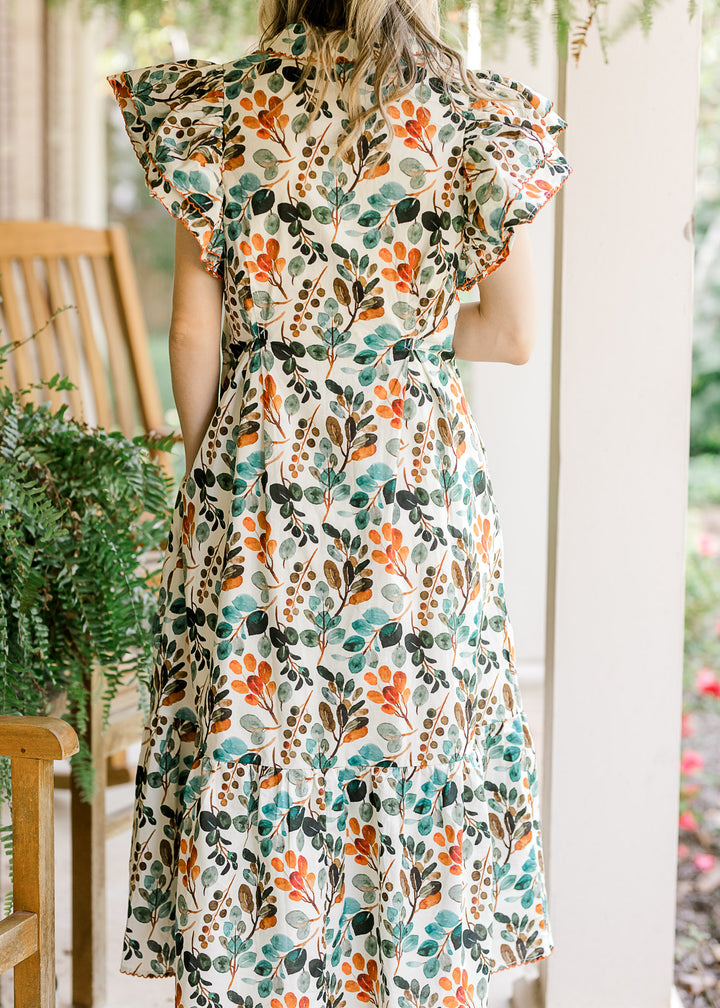 Back view of Model wearing a cream midi with fall floral, layered flutter cap sleeves and a collar.