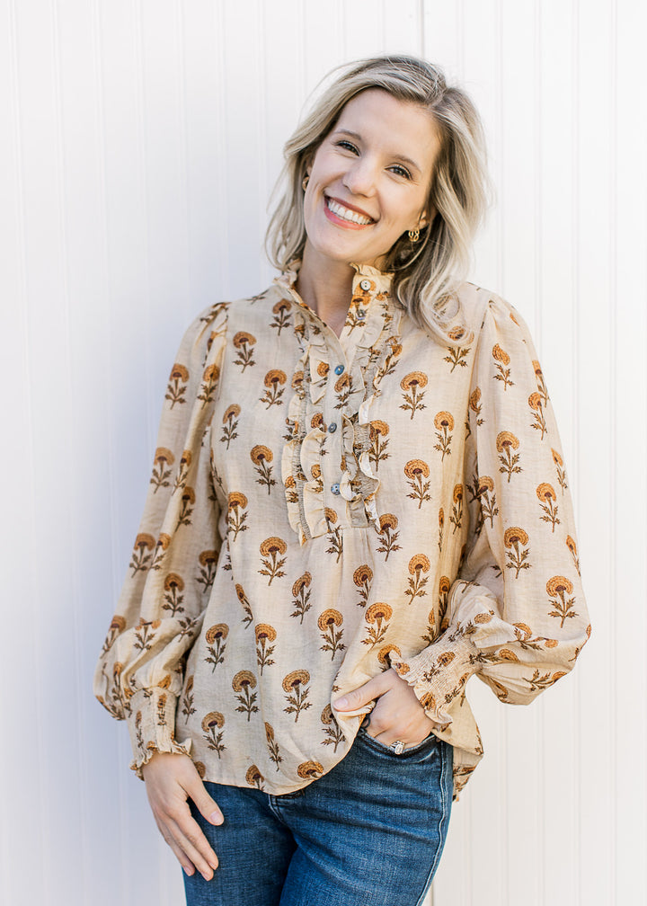 Model wearing jeans and a camel top with mustard floral, ruffle placket and poet long sleeves.