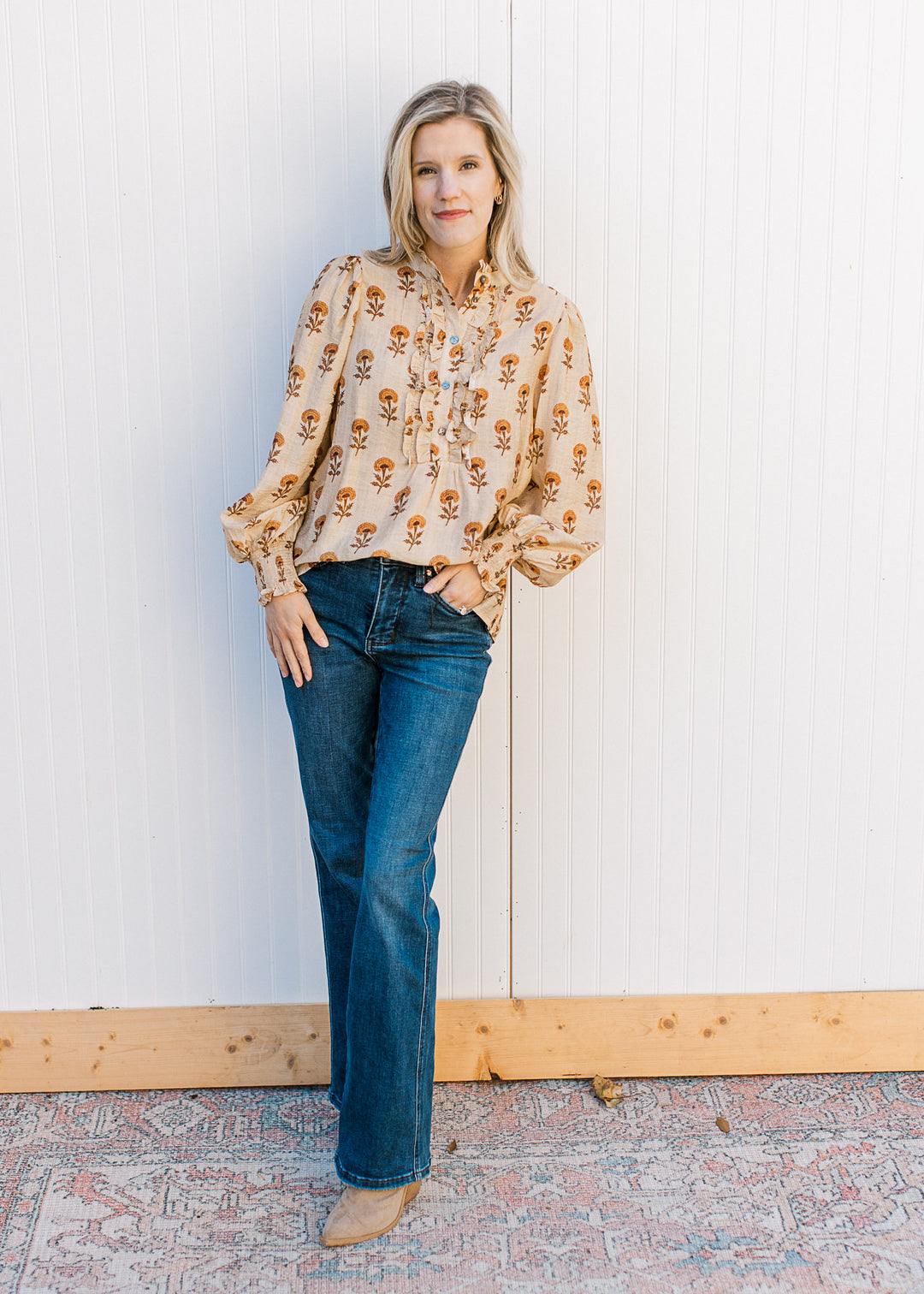 Model wearing jeans, boots and a camel top with mustard floral and poet long sleeves.