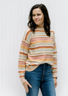 Model wearing a textured sweater striped with fall colors having long sleeves and a round neck. 