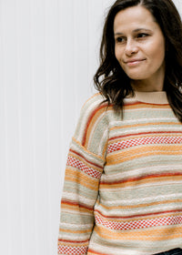 Close up of textured sweater with striped fall colors, long sleeves and a round neck. 