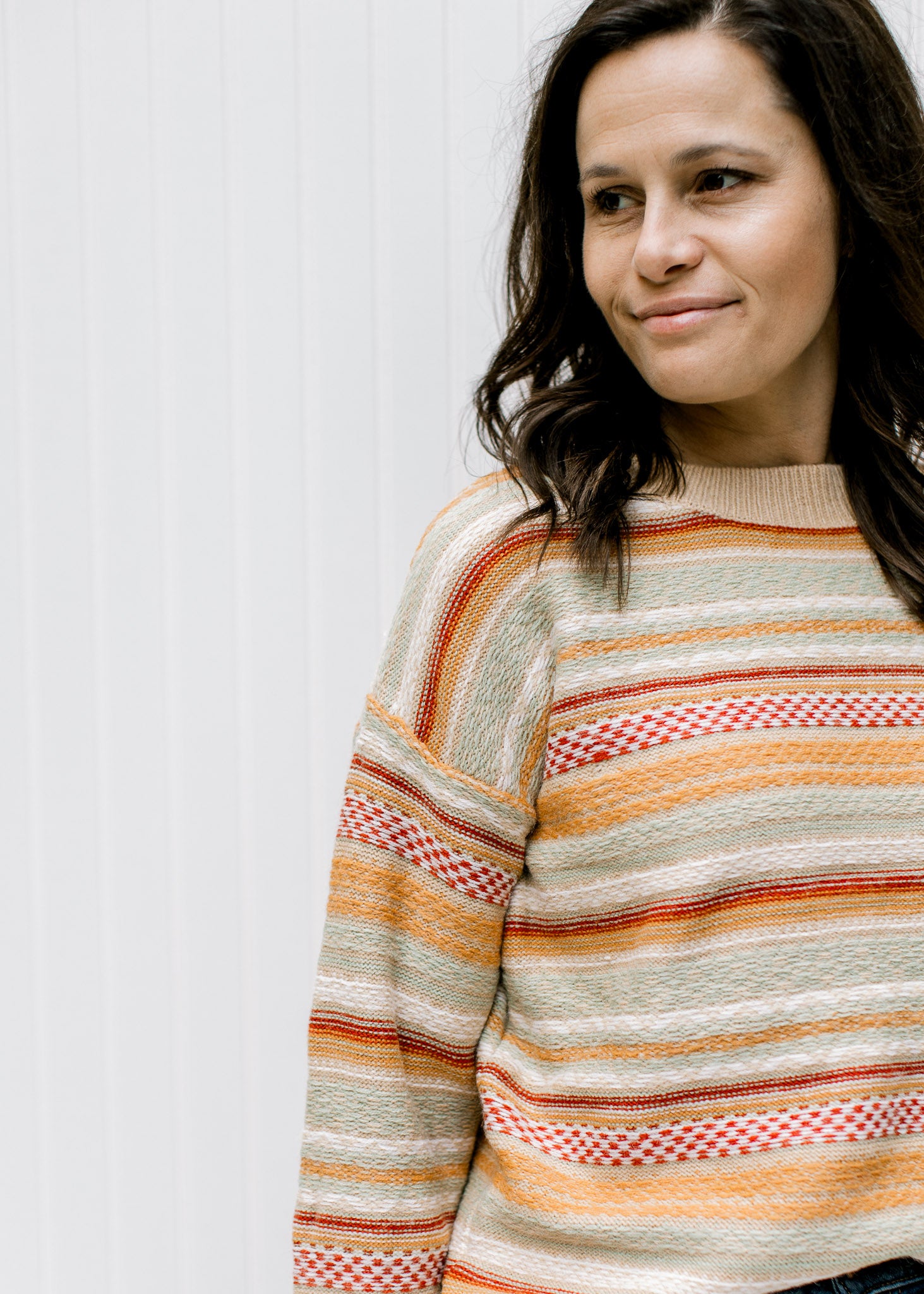 Close up of textured sweater with striped fall colors, long sleeves and a round neck. 