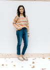 Model wearing jeans with a textured sweater with striped fall colors, long sleeves and a round neck.