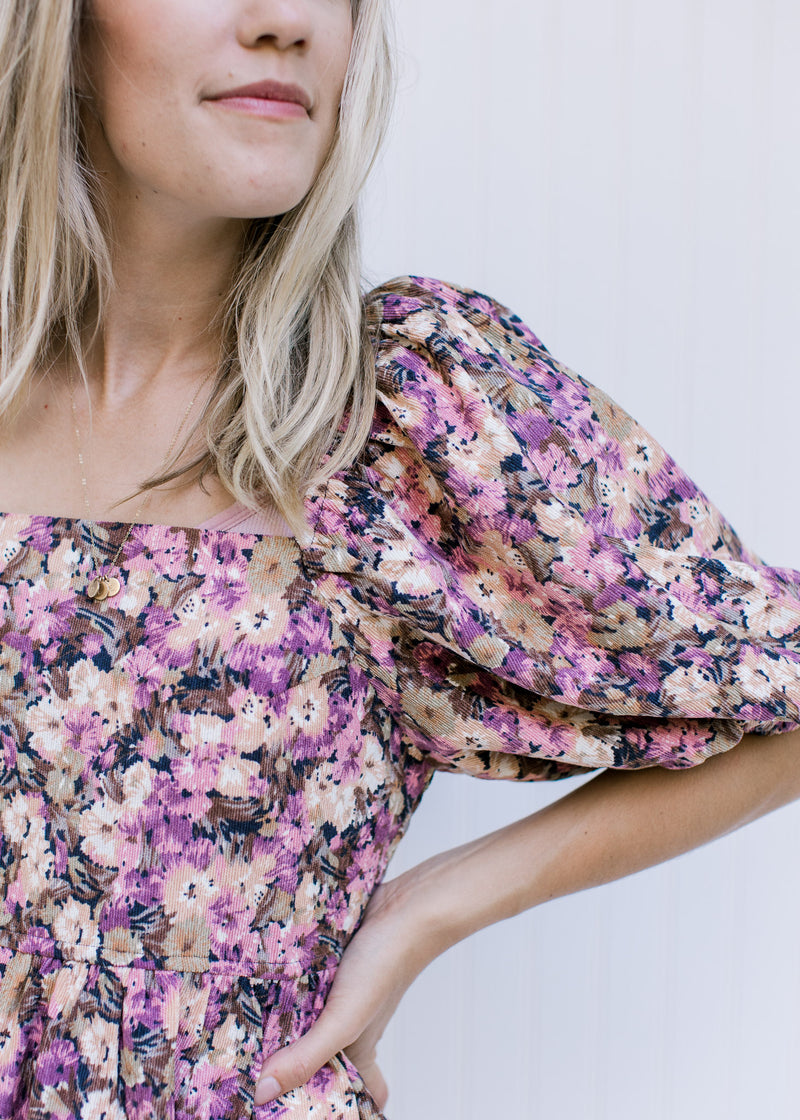 Close up of square neckline, bubble short sleeve and corduroy material on a floral midi dress. 