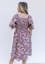 Back view of Model wearing a floral corduroy midi dress with a square neckline and a smocked back.