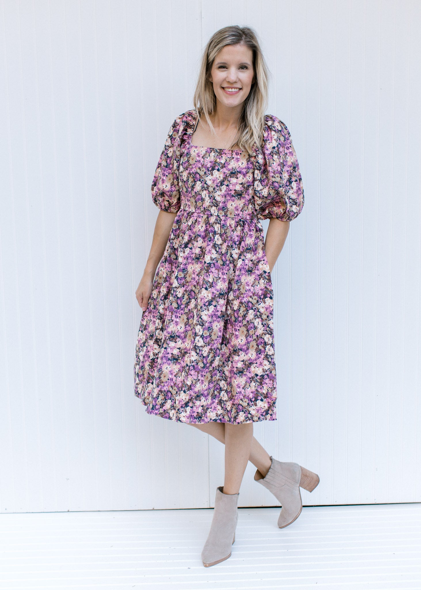 Model wearing booties with a floral dress with a square neck, smocked back and bubble short sleeves.