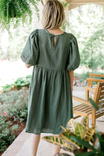 Back view of Model wearing a sage, gauze dress with bubble short sleeves and a keyhole closure. 