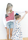 Model with child wearing a white lightweight knit sweater with a flag pattern and long sleeves.