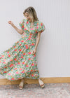 Model wearing a bright floral maxi with short puff sleeves, elastic waist and a v-neck. 