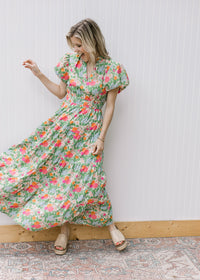 Model wearing a bright floral maxi with short puff sleeves, elastic waist and a v-neck. 