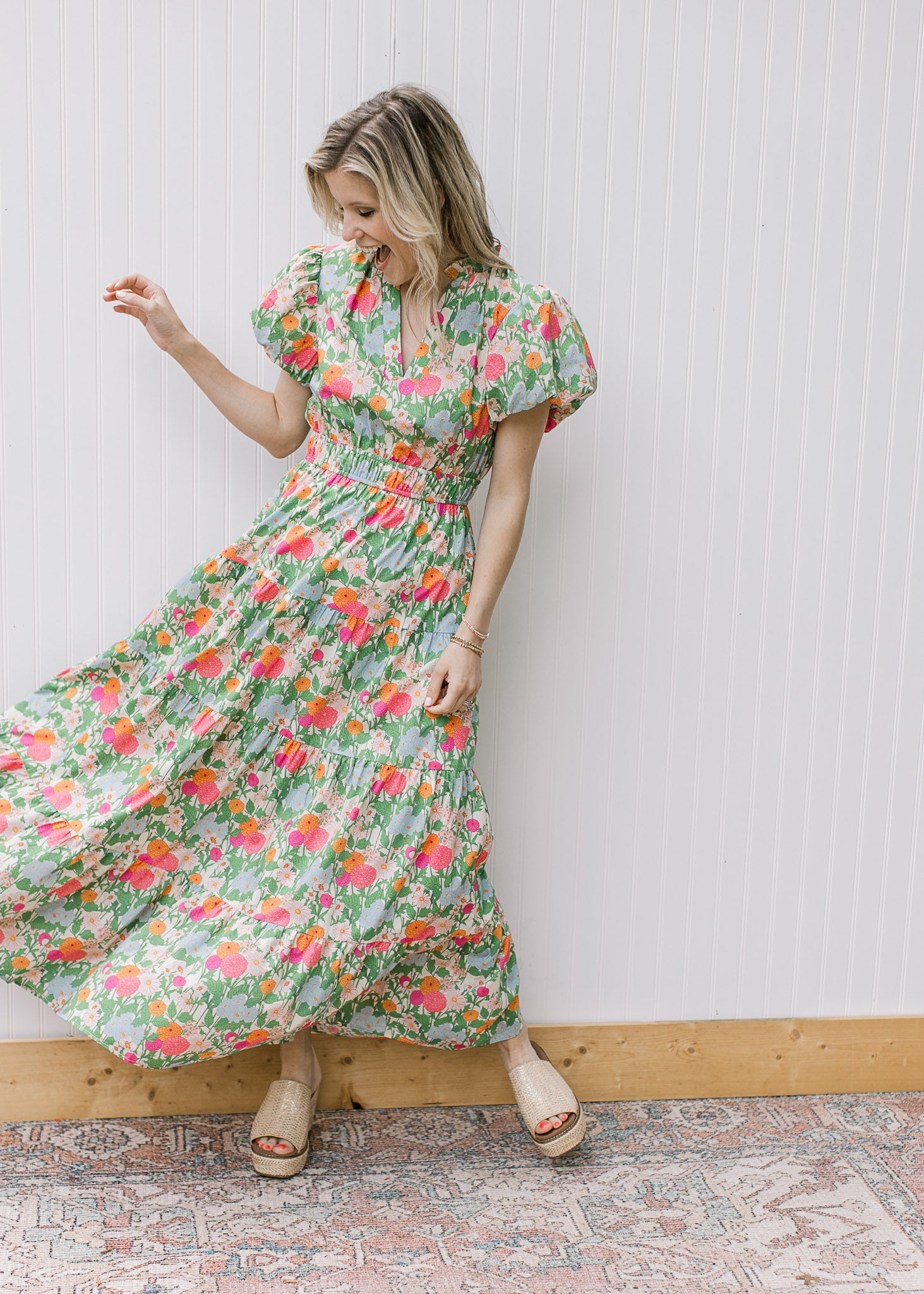 Model wearing a bright floral maxi with short puff sleeves, elastic waist and a v-neck. 