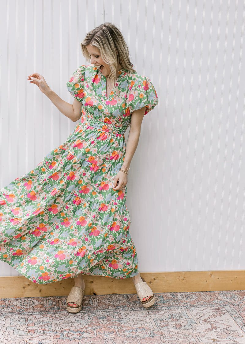 Model wearing a bright floral maxi with short puff sleeves, elastic waist and a v-neck. 