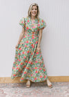 Model wearing a bright floral maxi with elastic waist and short puff sleeve with pleated shoulder. 
