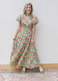 Model wearing a bright floral maxi with elastic waist and short puff sleeve with pleated shoulder. 