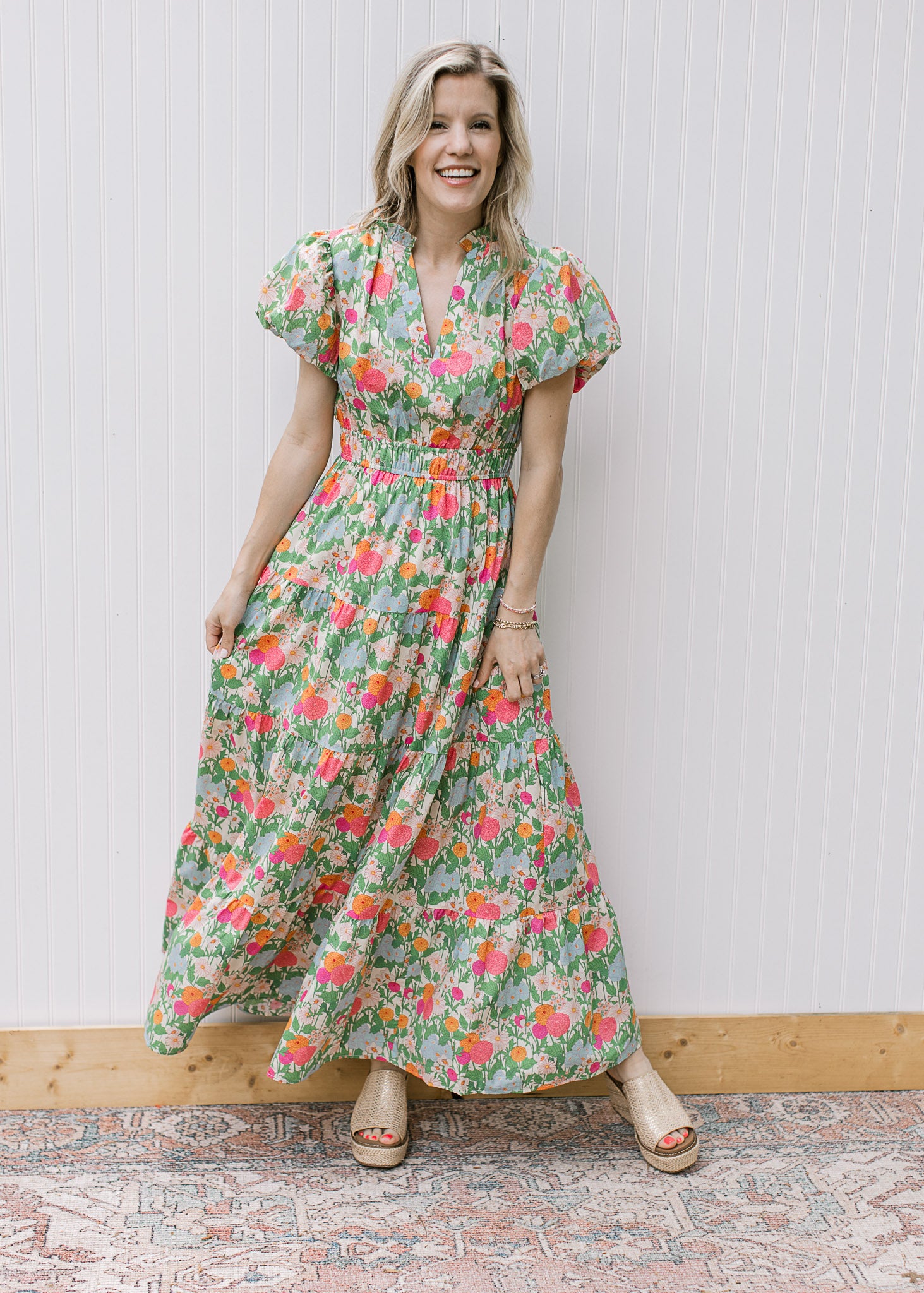 Model wearing a bright floral maxi with elastic waist and short puff sleeve with pleated shoulder. 