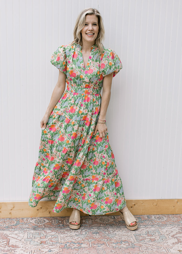 Model wearing a bright floral maxi with elastic waist and short puff sleeve with pleated shoulder. 
