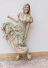 Model wearing a bright, flowy floral maxi with short puff sleeves, elastic waist and a v-neck. 
