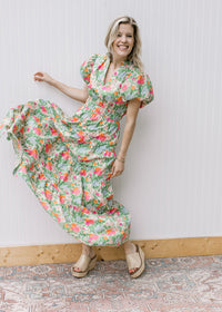 Model wearing a bright, flowy floral maxi with short puff sleeves, elastic waist and a v-neck. 