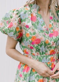 Close up of short puff sleeve, v-neck, ruffle neck and smocked bodice on bright floral maxi. 